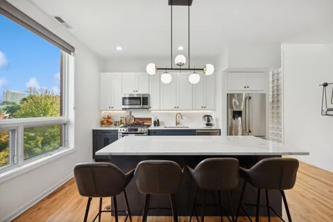 a large kitchen with granite countertop a table chairs stainless steel appliances and wooden floor