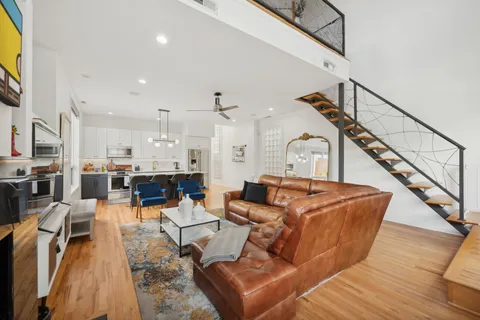 a living room with furniture kitchen view and a chandelier