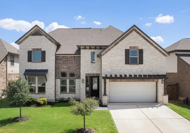 a front view of a house with a yard and trees