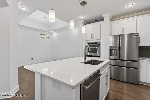 a large kitchen with stainless steel appliances granite countertop a stove a sink dishwasher and white cabinets with wooden floor