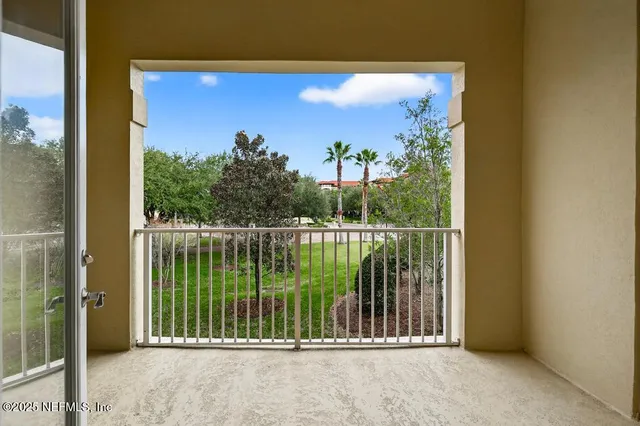 a view of a patio with couches table and chairs under an umbrella with palm trees