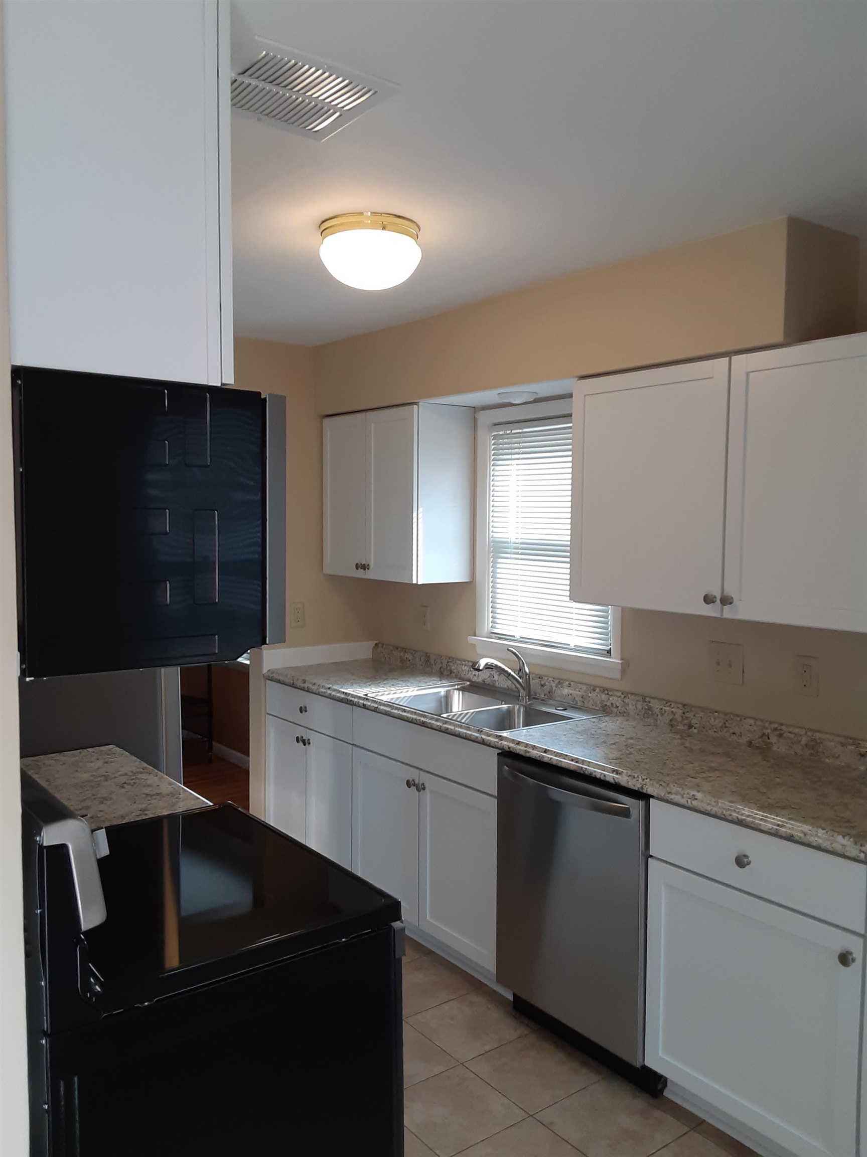 937 West Arrowhead Road Duluth, MN 55811 - Photo 5 of 23 Kitchen with black electric range oven, dishwasher, white cabinets, and light tile patterned floors.