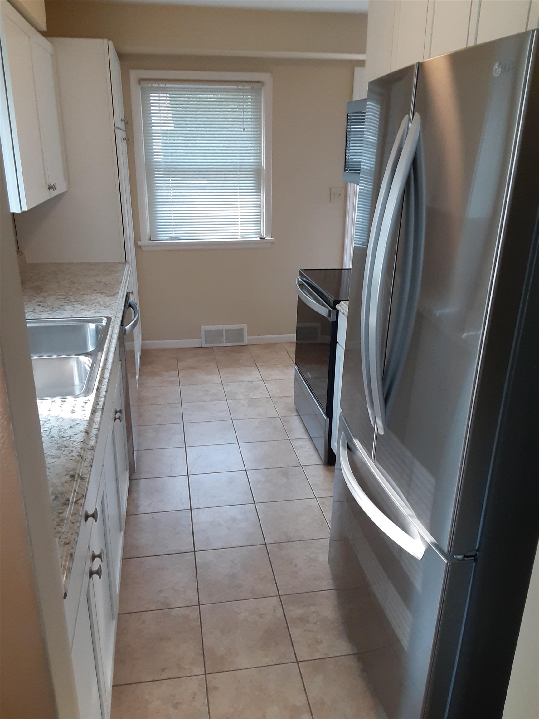 937 West Arrowhead Road Duluth, MN 55811 - Photo 6 of 23 Kitchen featuring freestanding refrigerator, white cabinetry, light tile patterned floors, black / electric stove, and light countertops.