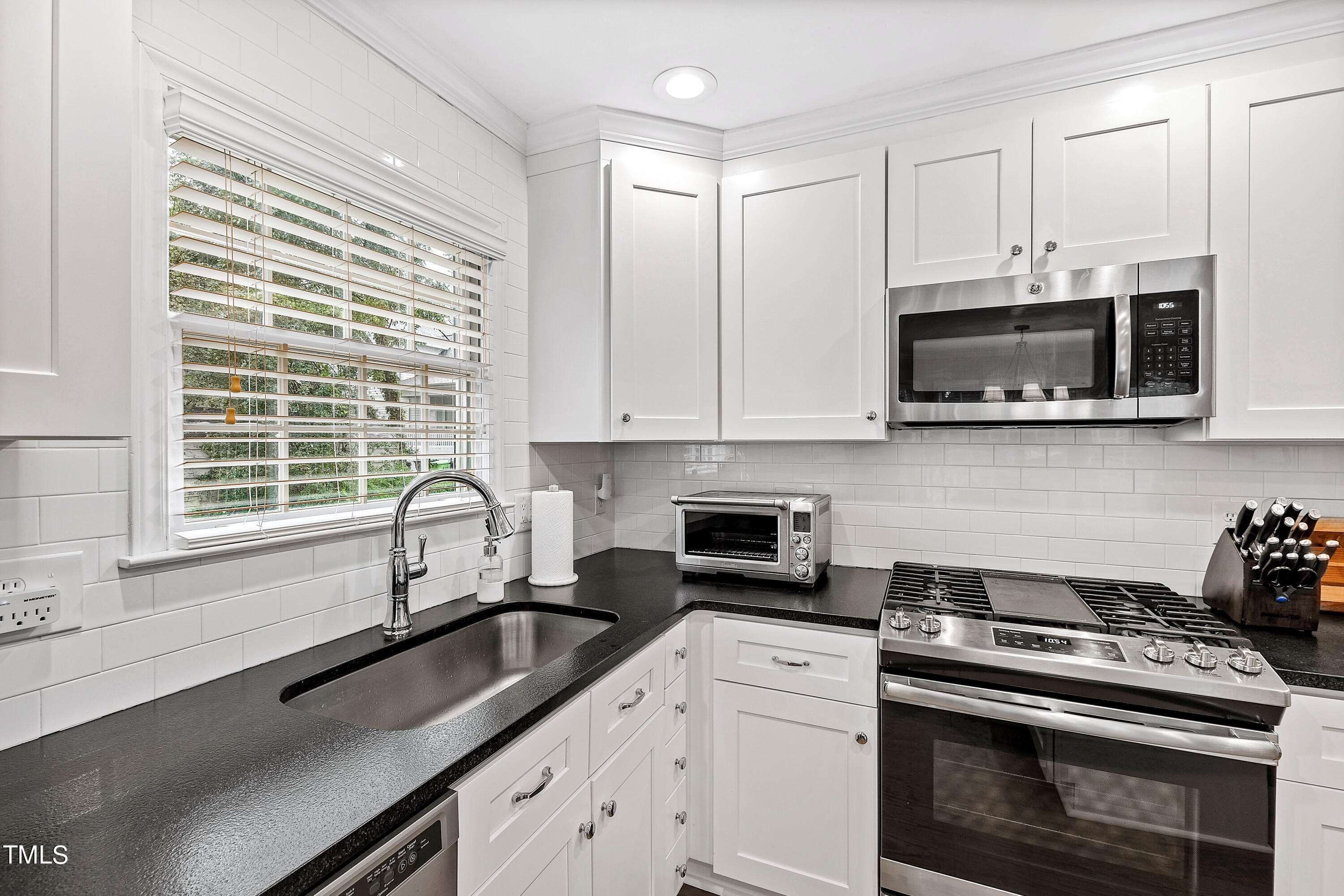 1816 Ridley Street Raleigh, NC 27608 - Photo 17 of 40 a kitchen with stainless steel appliances a stove a microwave a sink and cabinets