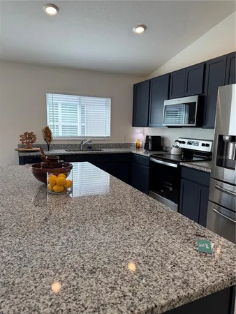 a kitchen with stainless steel appliances granite countertop a stove a sink and a refrigerator
