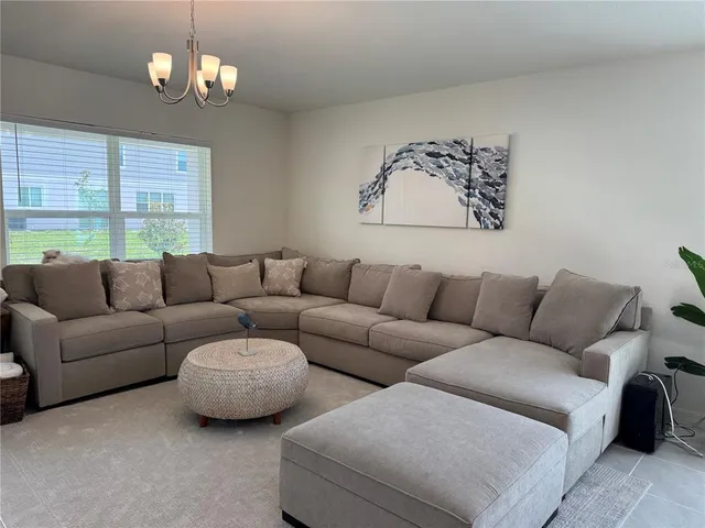 a living room with furniture a large window and a chandelier
