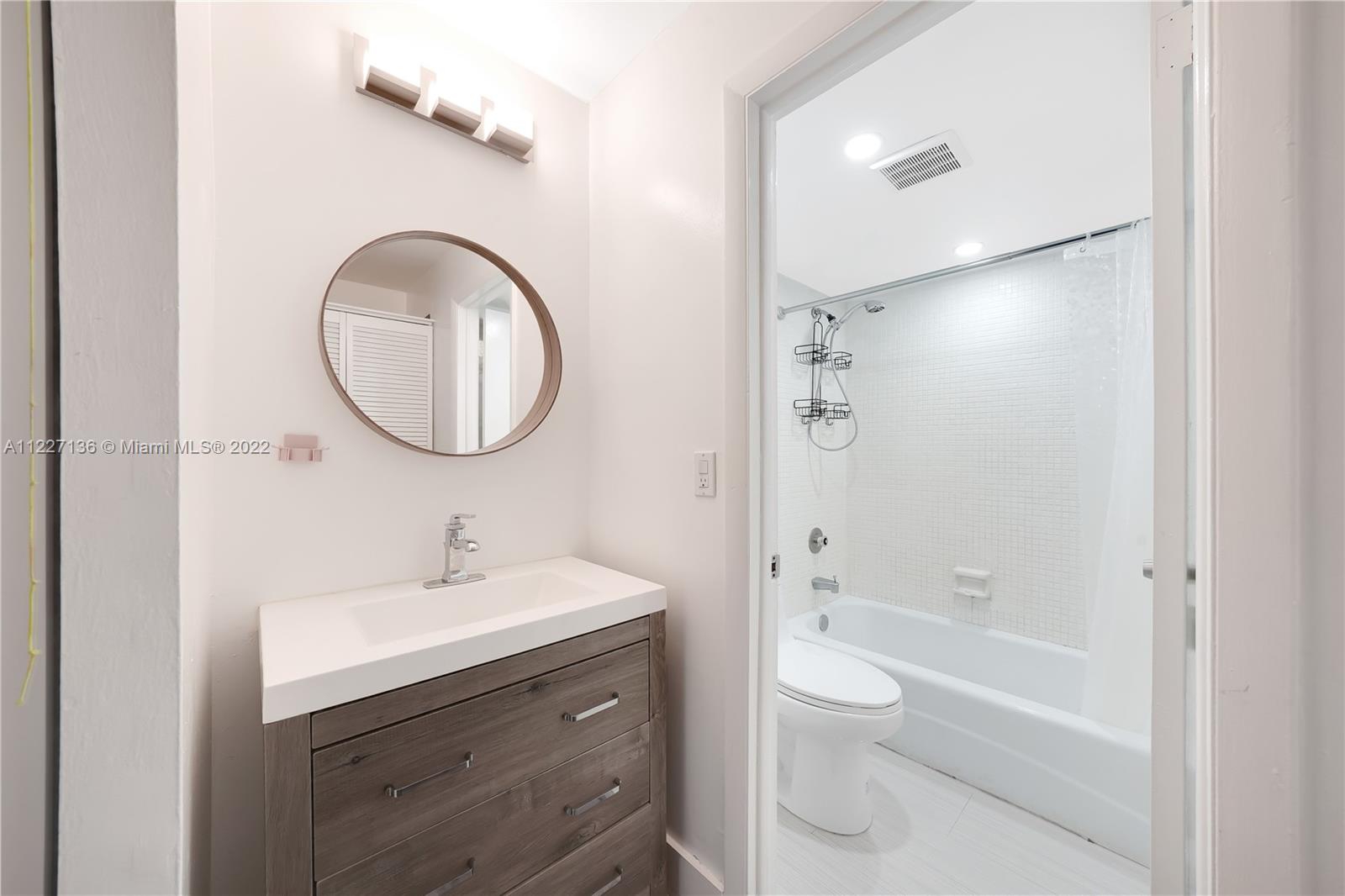 3670 Inverrary Drive, Unit 1I Lauderhill, FL 33319 - Photo 11 of 14 a bathroom with a bathtub shower sink mirror and toilet