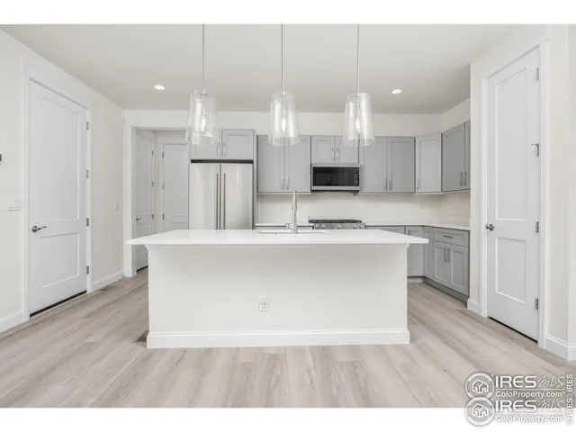 a large white kitchen with kitchen island white cabinets and stainless steel appliances