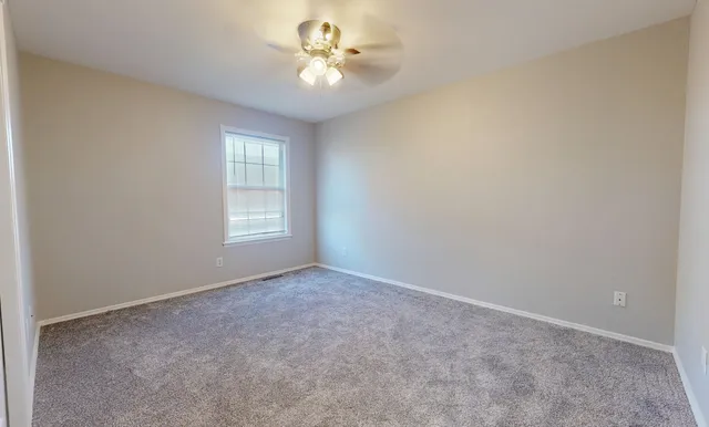 an empty room with windows and ceiling fan