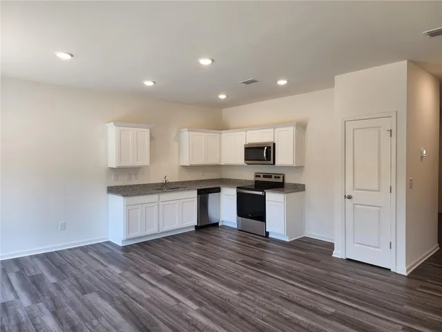 a kitchen with granite countertop a stove top oven and cabinets