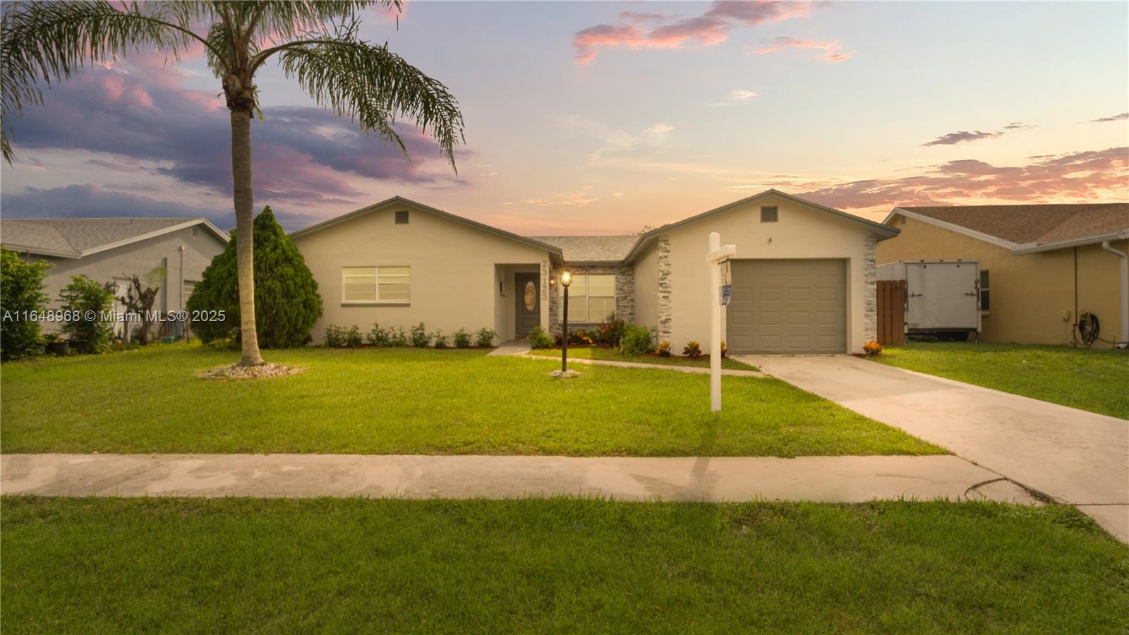 23123 Southwest 58th Avenue Boca Raton, FL 33428 - Photo 1 of 1 a front view of a house with a yard and palm trees