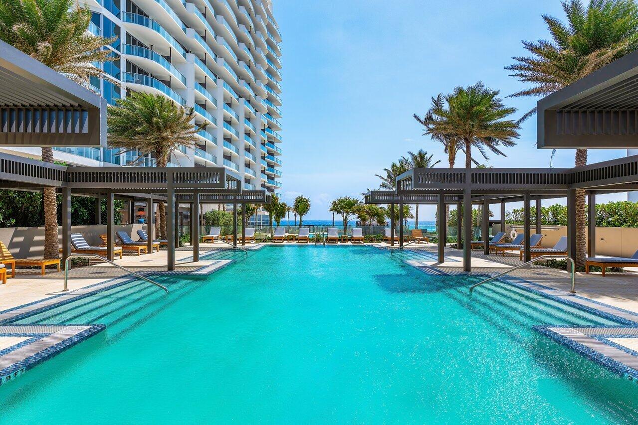 3100 North Ocean Drive, Unit 1505 Riviera Beach, FL 33404 - Photo 48 of 60 a view of a swimming pool with lawn chairs and plants