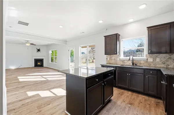 a kitchen with granite countertop a sink and a stove top oven with wooden floor