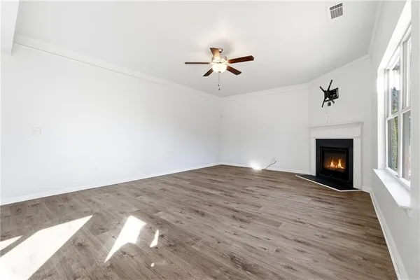 a view of empty room with wooden floor and fan