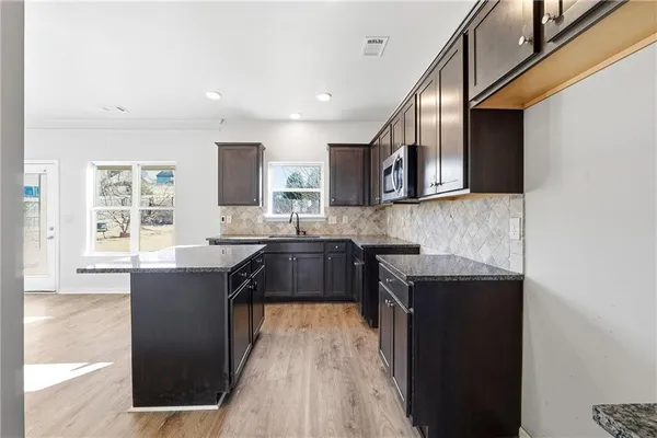 a kitchen with stainless steel appliances granite countertop a stove a sink and a microwave