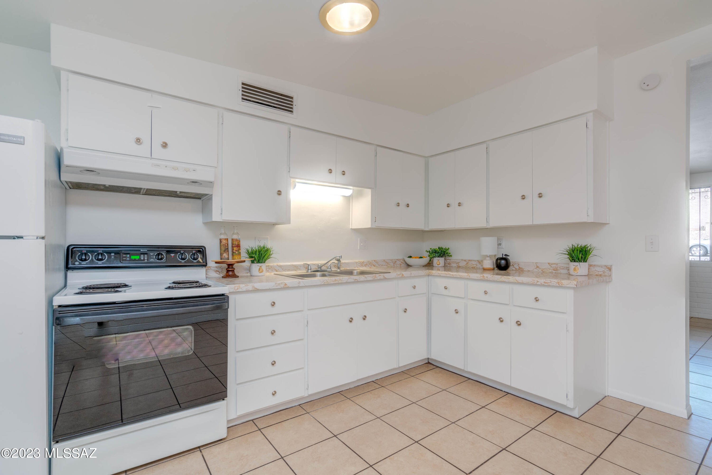 1845 West Caravelle Road Tucson, AZ 85713 - Photo 6 of 31 a kitchen with granite countertop white cabinets and white appliances
