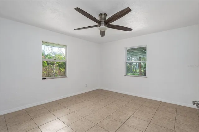 an empty room with ceiling fan and windows