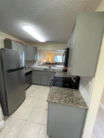 a kitchen with granite countertop a refrigerator and a stove top oven