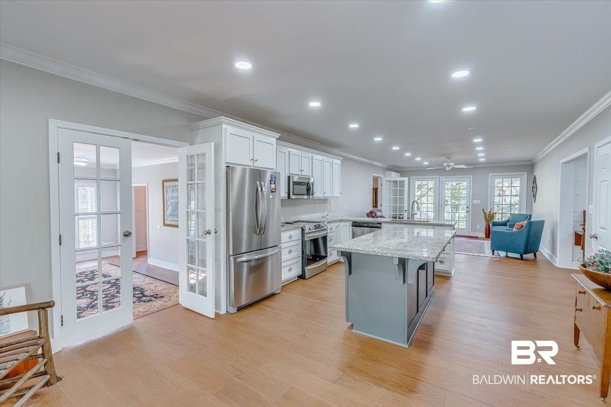 14160 Moffett Road Wilmer, AL 36587 - Photo 4 of 75 Kitchen featuring white cabinets, a breakfast bar, appliances with stainless steel finishes, light wood-type flooring, and french doors