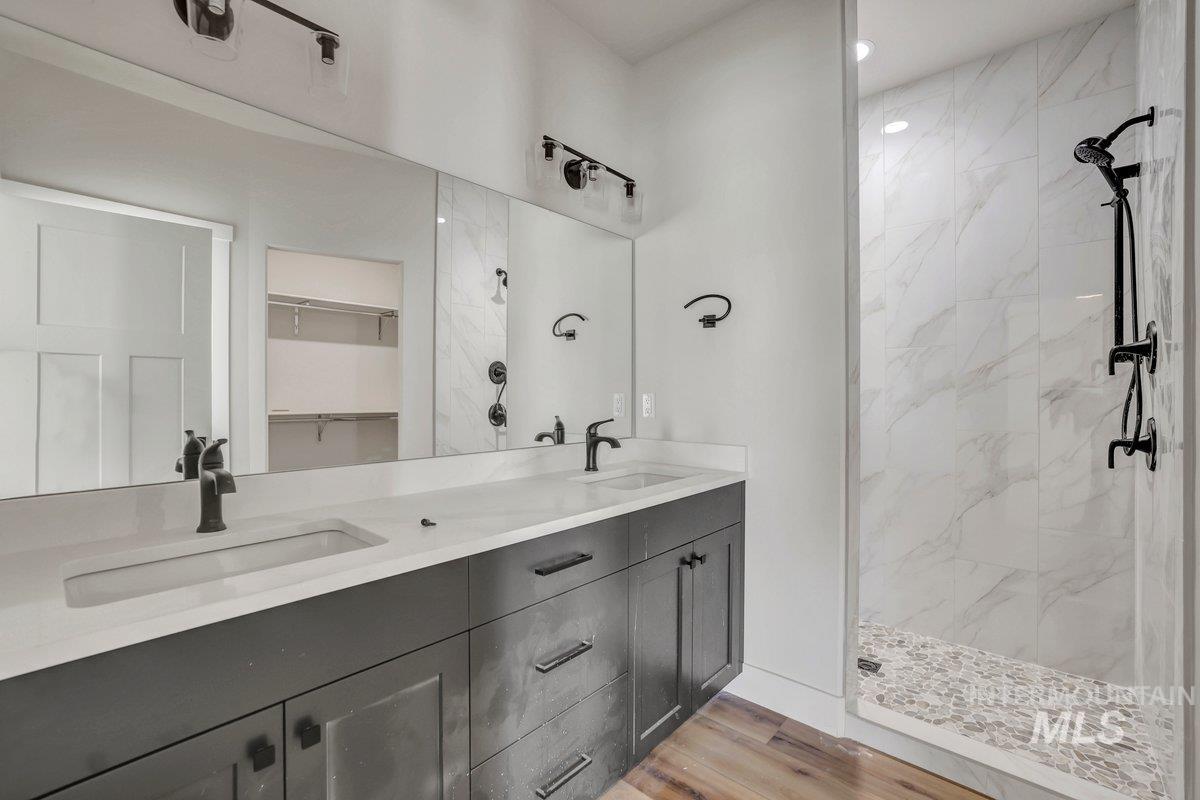 951 Gregory Way Twin Falls, ID 83301 - Photo 15 of 31 Bathroom featuring a shower stall, double vanity, wood finished floors, and a walk in closet