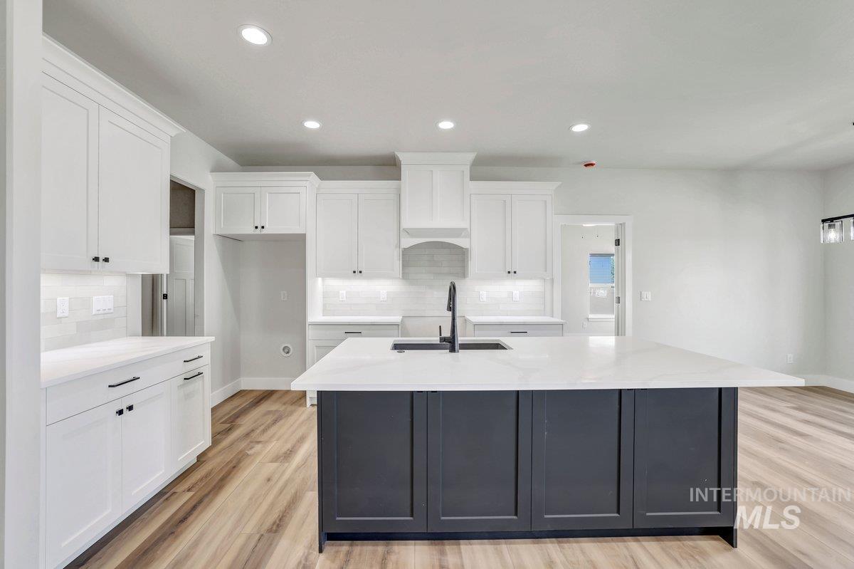 951 Gregory Way Twin Falls, ID 83301 - Photo 5 of 31 Kitchen with tasteful backsplash, a kitchen island with sink, white cabinets, light wood finished floors, and recessed lighting