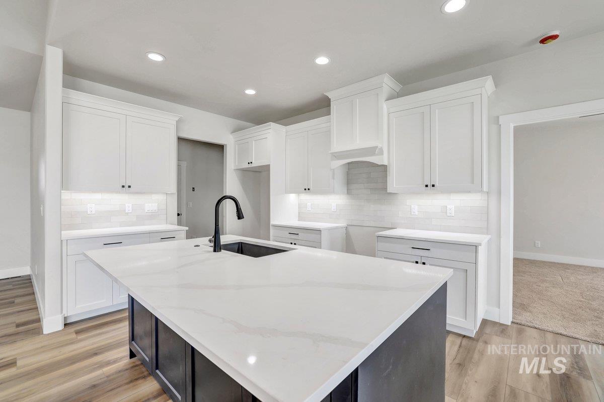 951 Gregory Way Twin Falls, ID 83301 - Photo 6 of 31 Kitchen featuring a kitchen island with sink, white cabinets, decorative backsplash, light wood-type flooring, and recessed lighting