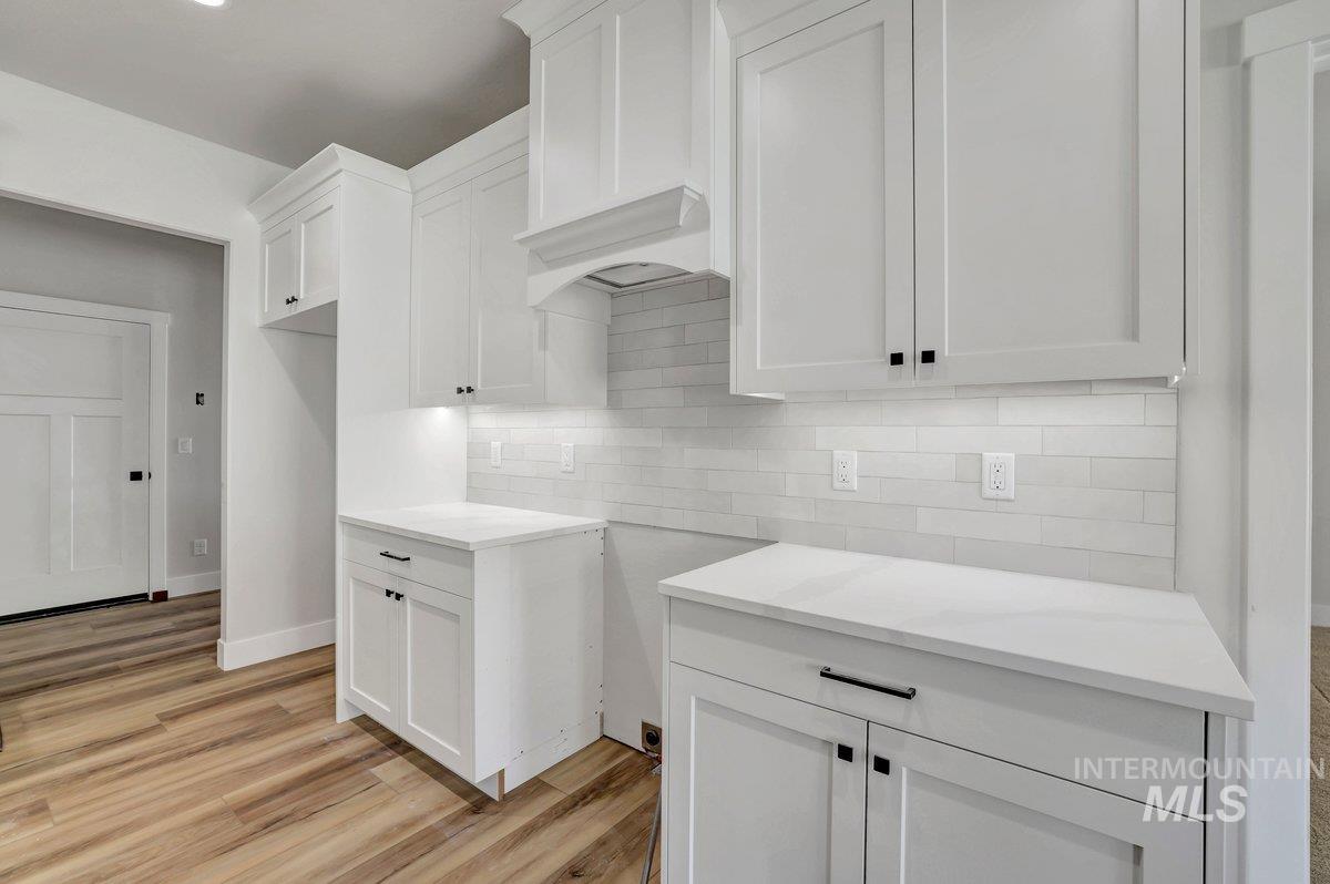 951 Gregory Way Twin Falls, ID 83301 - Photo 7 of 31 Kitchen featuring white cabinets, tasteful backsplash, light wood-type flooring, and light stone countertops