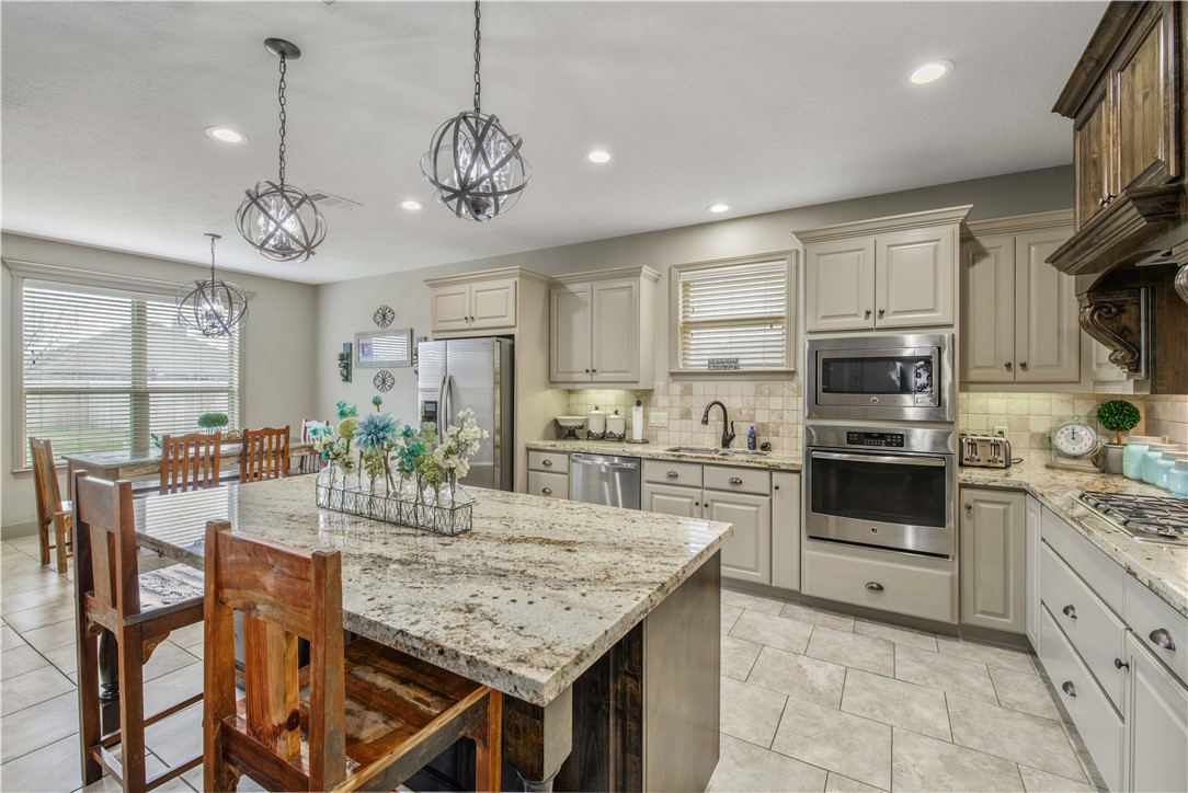 3049 Embers Loop Bryan, TX 77808 - Photo 8 of 21 a kitchen with stainless steel appliances granite countertop a stove top oven a refrigerator a sink dishwasher a dining table and chairs with wooden floor