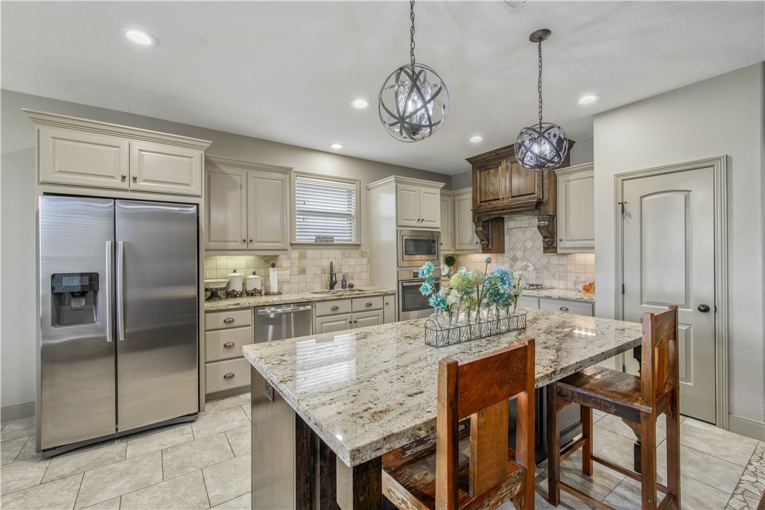 3049 Embers Loop Bryan, TX 77808 - Photo 9 of 21 a kitchen with stainless steel appliances granite countertop a refrigerator a stove a kitchen island a dining table and chairs