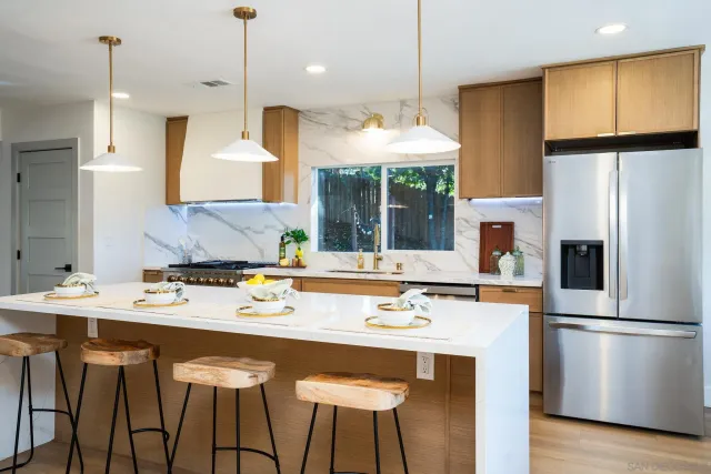 a kitchen with stainless steel appliances granite countertop a sink a stove a refrigerator and island with wooden floor