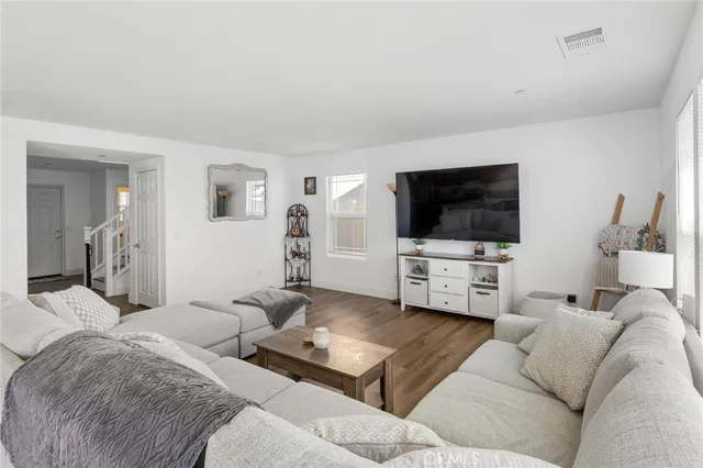 a living room with stainless steel appliances furniture and a wooden floor
