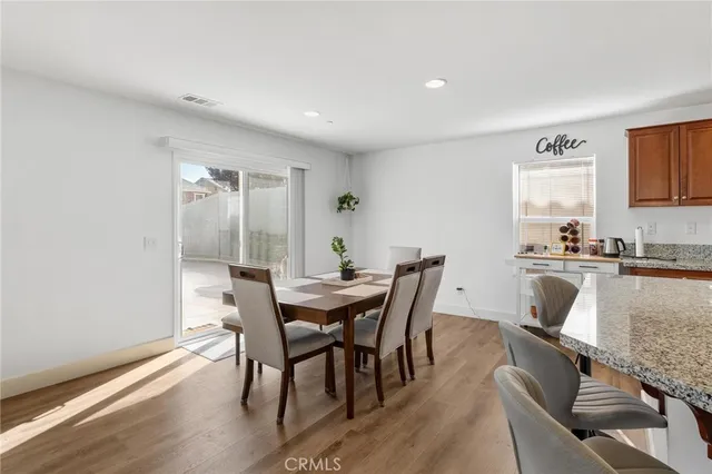 a kitchen with stainless steel appliances granite countertop a refrigerator a stove a sink a dining table and chairs with wooden floor