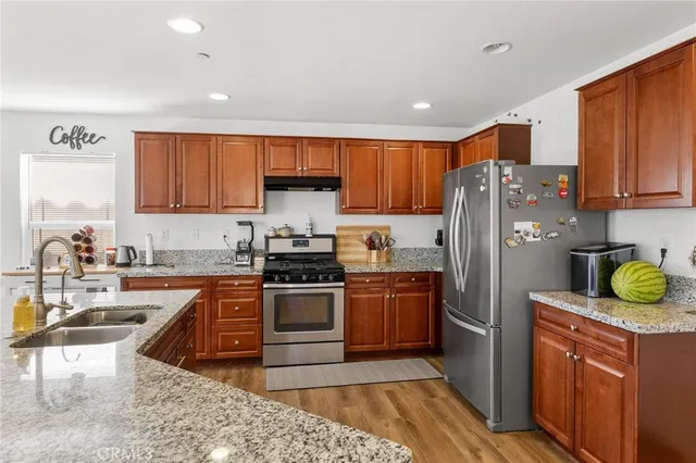 a kitchen with stainless steel appliances granite countertop a refrigerator stove and wooden cabinets
