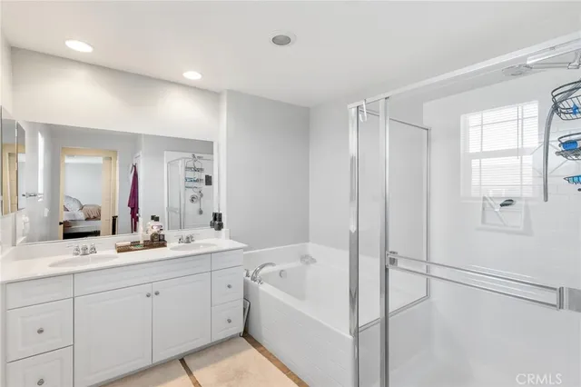 a en suite bathroom with a double vanity sink a mirror and a bathtub