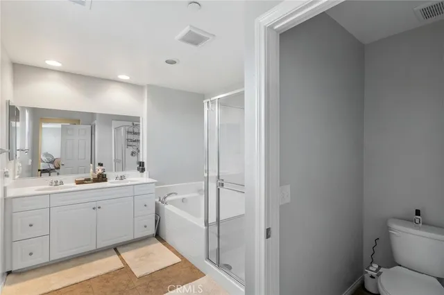 a bathroom with a double vanity sink toilet mirror and bathtub
