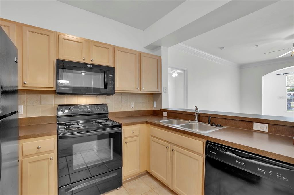 12831 Madison Pointe Circle, Unit 107 Orlando, FL 32821 - Photo 3 of 11 a kitchen with stainless steel appliances granite countertop a sink stove and microwave