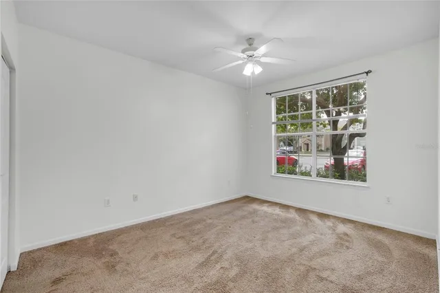 an empty room with windows and fan
