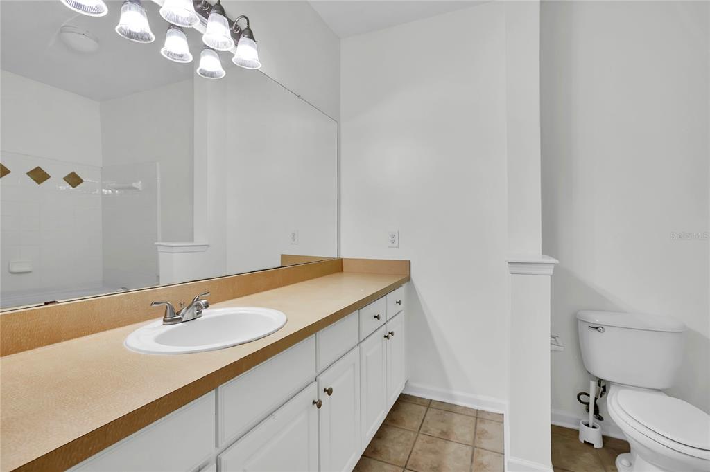 12831 Madison Pointe Circle, Unit 107 Orlando, FL 32821 - Photo 10 of 11 a bathroom with a granite countertop sink a toilet and a mirror