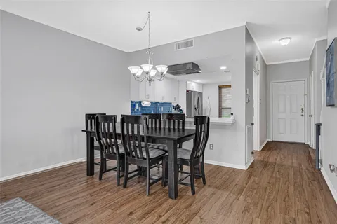 a dining room with furniture wooden floor a rug a potted plant and a chandelier