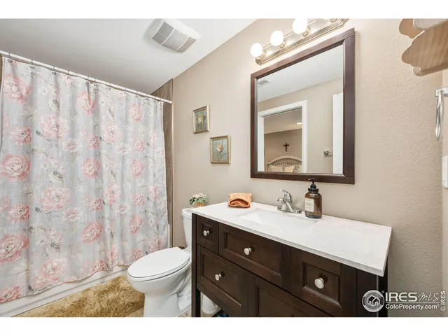 a bathroom with a toilet a sink a mirror a window and vanity