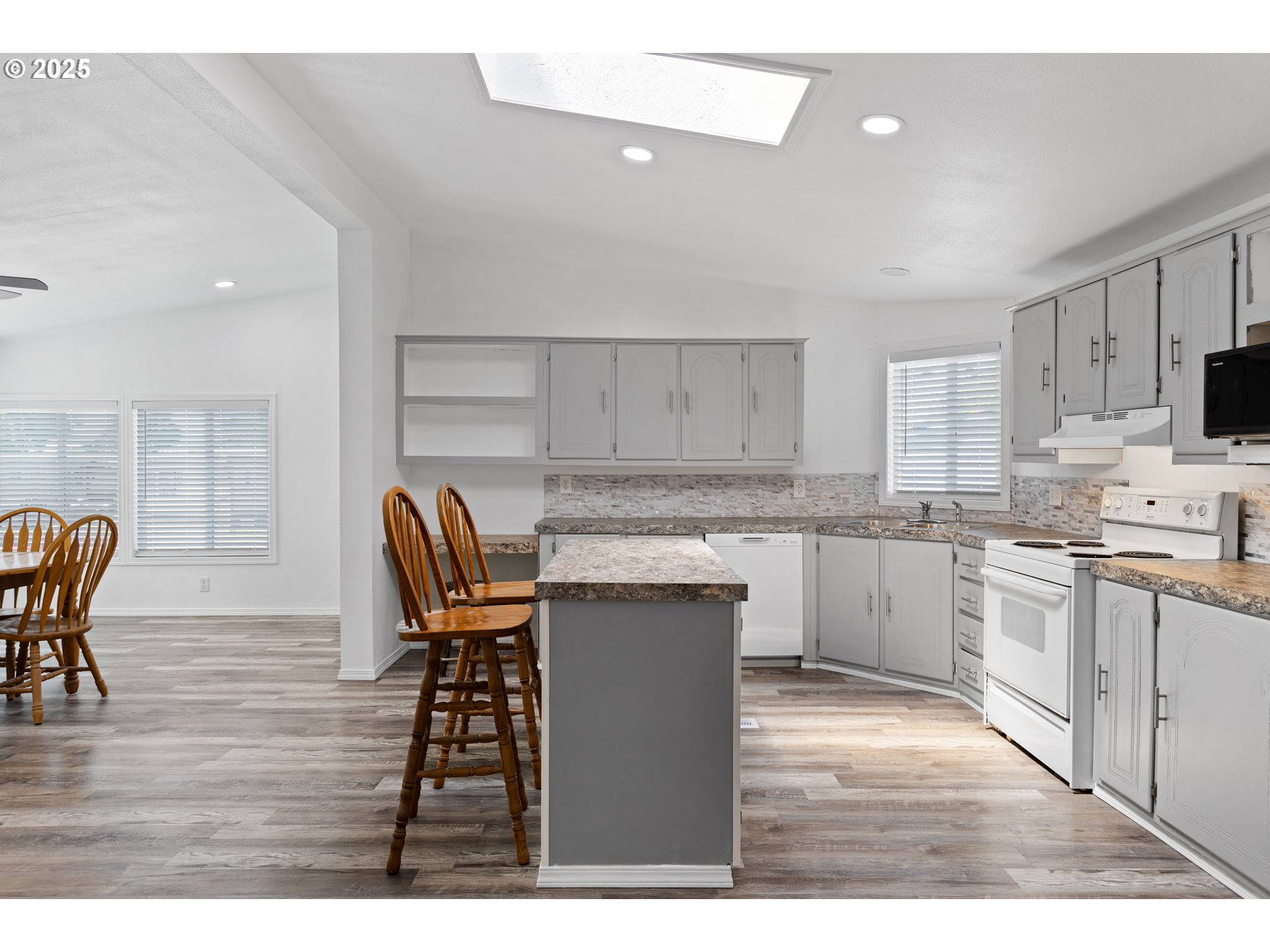 78 Manor Loop Roseburg, OR 97471 - Photo 16 of 45 a kitchen with kitchen island granite countertop a table chairs a sink dishwasher refrigerator and cabinets