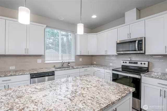 a kitchen with stainless steel appliances kitchen island granite countertop a stove sink and microwave