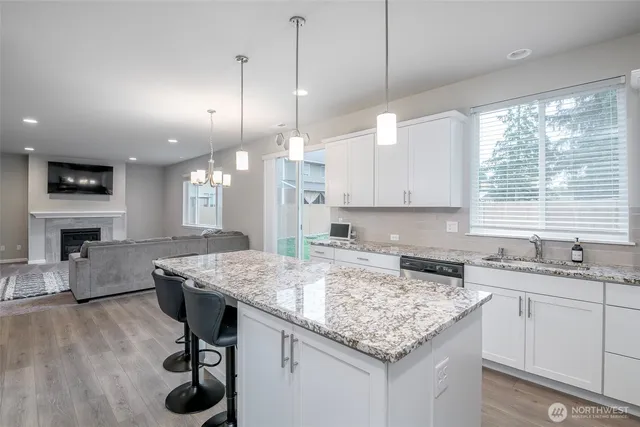 a kitchen with a stove center island a sink cabinets and a wooden floor