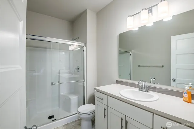 a bathroom with a shower sink vanity mirror and toilet