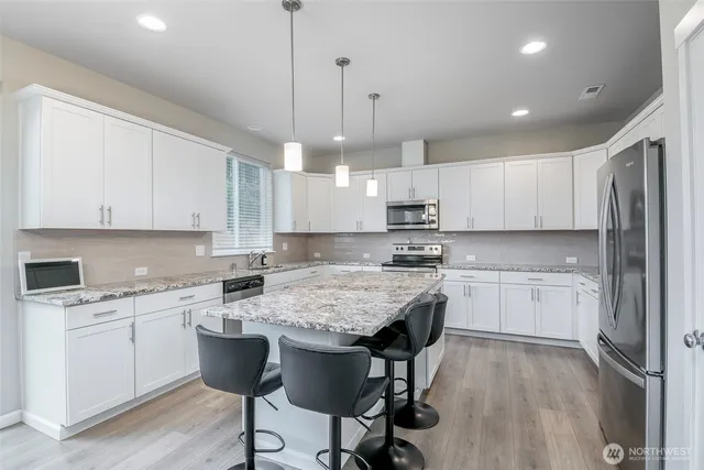 a kitchen with kitchen island granite countertop a sink a center island and cabinets