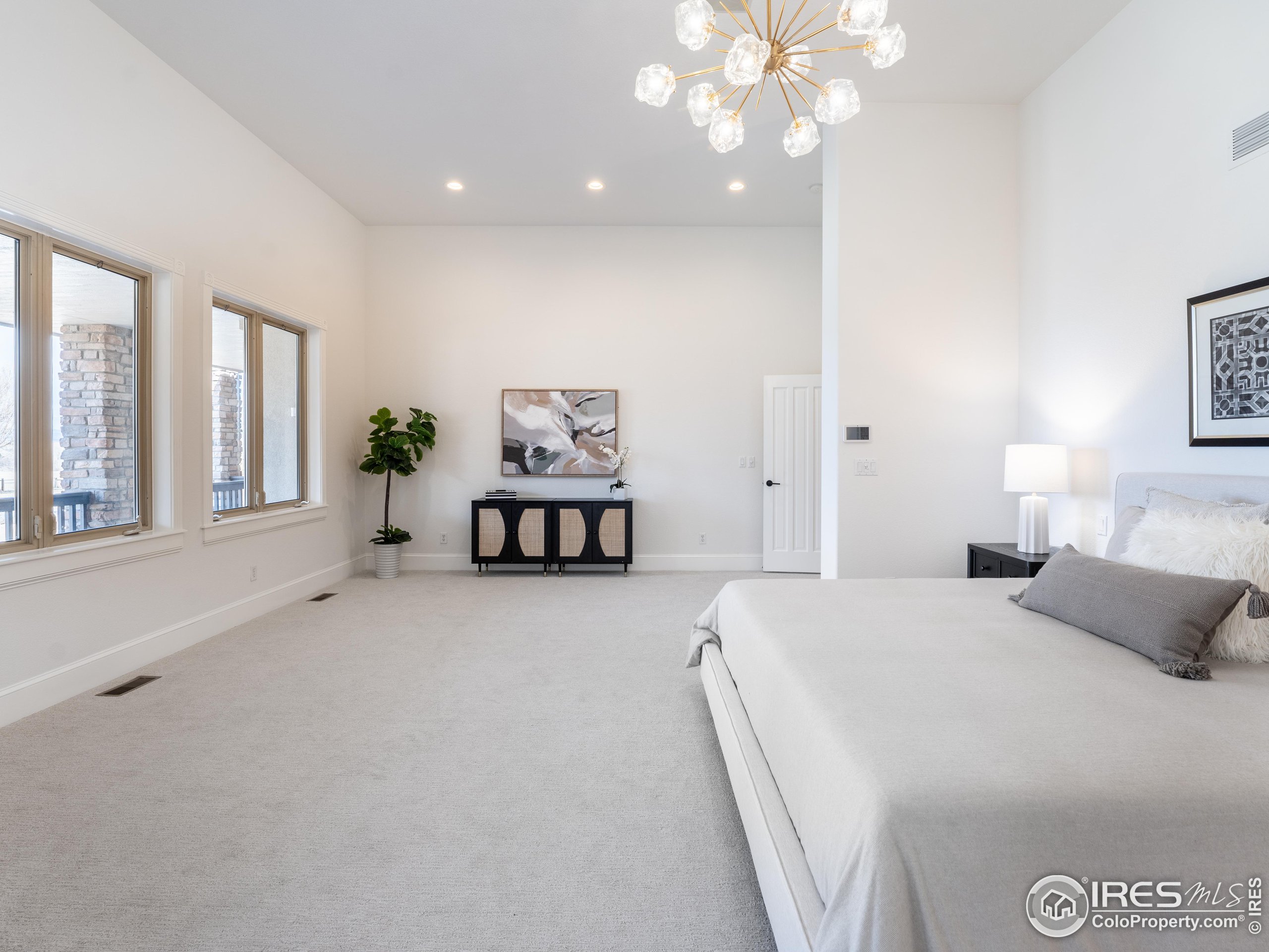 385 Baxter Farm Lane Erie, CO 80516 - Photo 22 of 40 a bedroom with a large bed and a chandelier