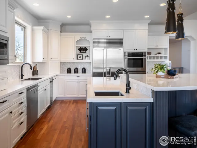 a kitchen with a sink white cabinets and stainless steel appliances