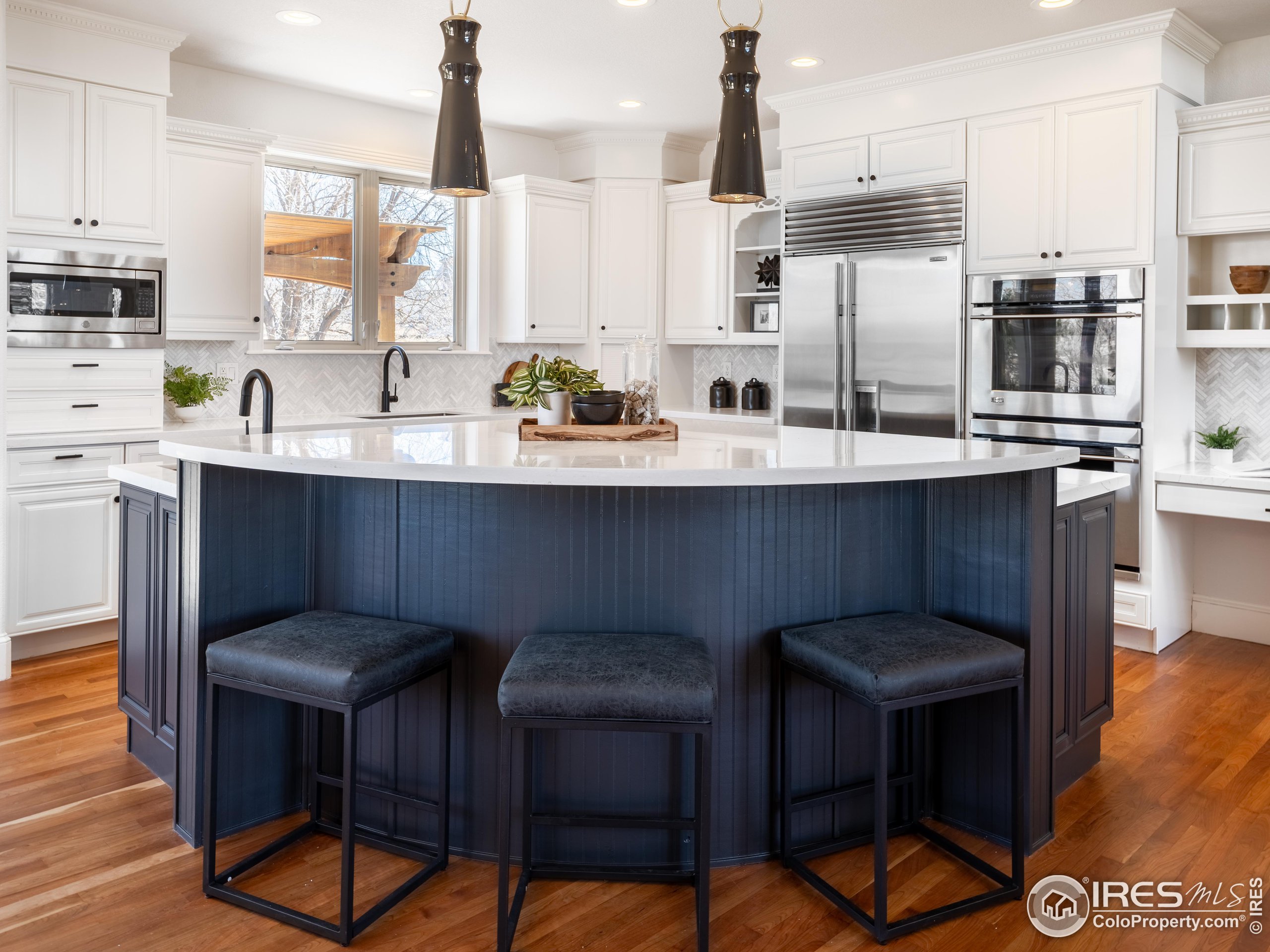 385 Baxter Farm Lane Erie, CO 80516 - Photo 10 of 40 a kitchen with stainless steel appliances a dining table chairs sink and cabinets