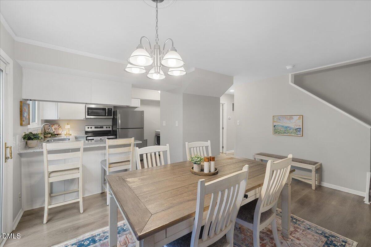 5821 Mapleridge Road Raleigh, NC 27609 - Photo 13 of 38 a view of a dining room with furniture a chandelier and wooden floor
