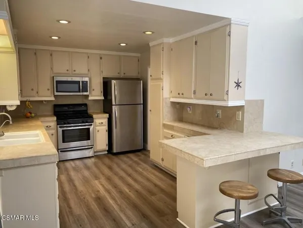 a kitchen with a refrigerator a stove and a microwave oven with wooden floor